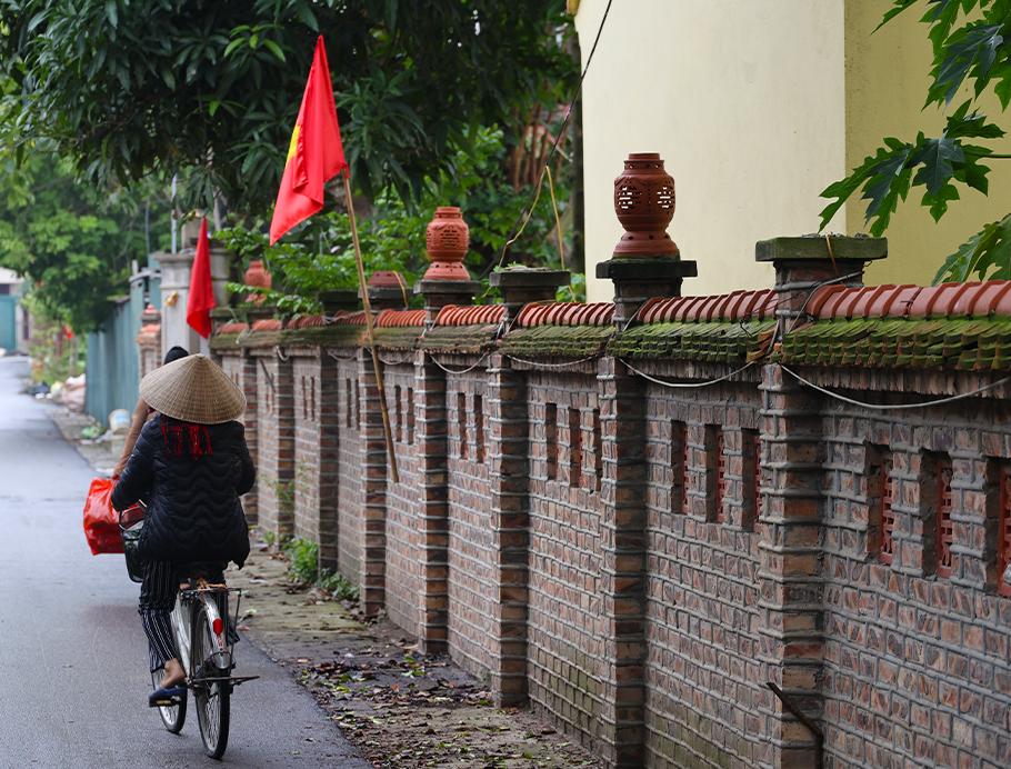A traditional lady cycling in Long Thuong Village in Hanoi, Vietnam on a Bunnik Tour to Vietnam